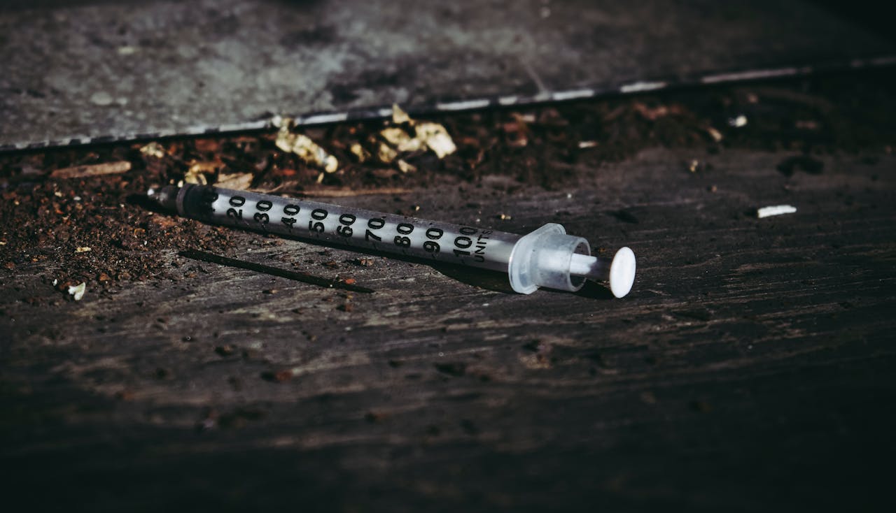 Close-up of a discarded syringe on a rough surface highlighting addiction issues.