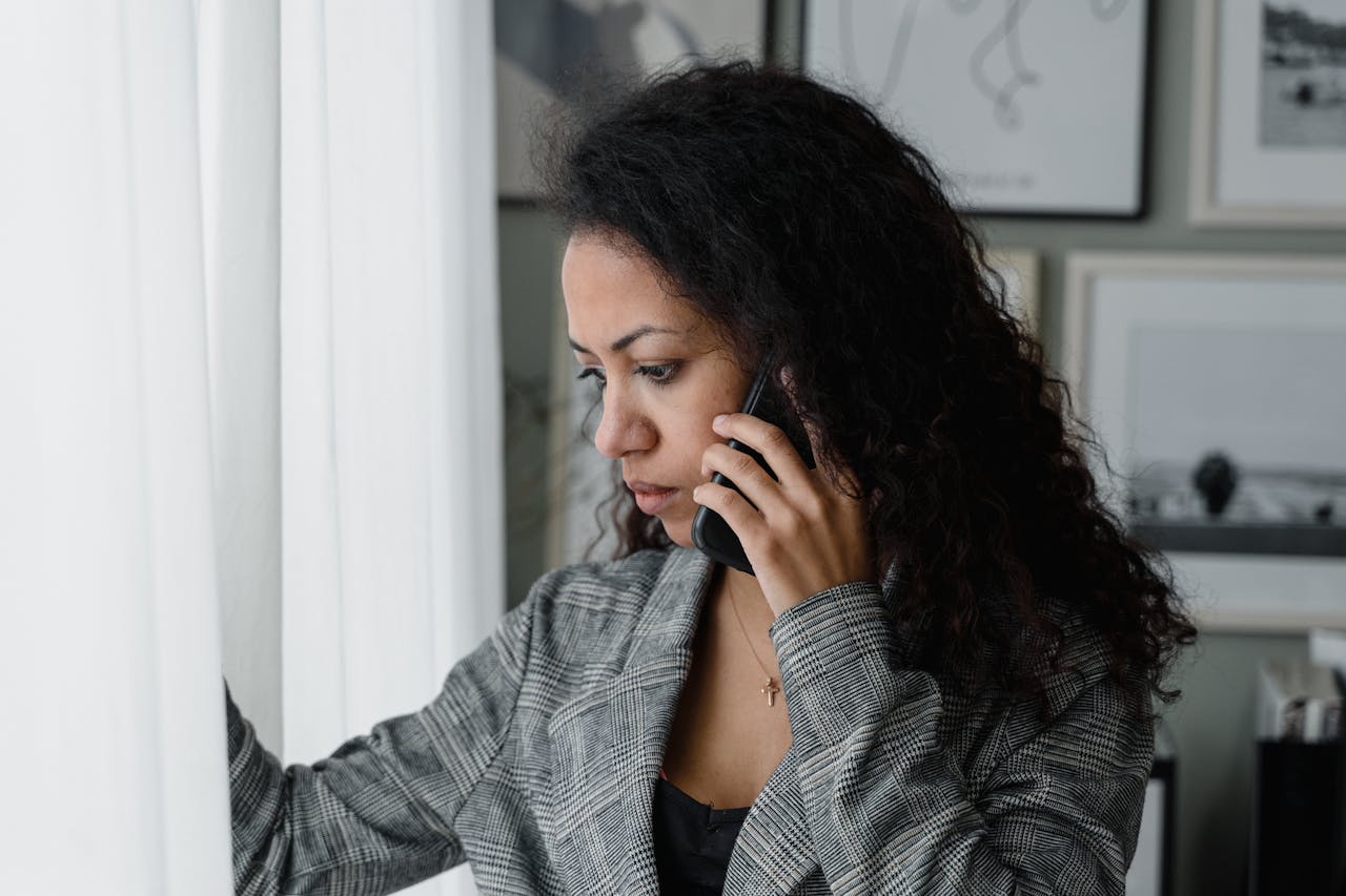 Businesswoman gazes outside while talking on the phone in an office setting.